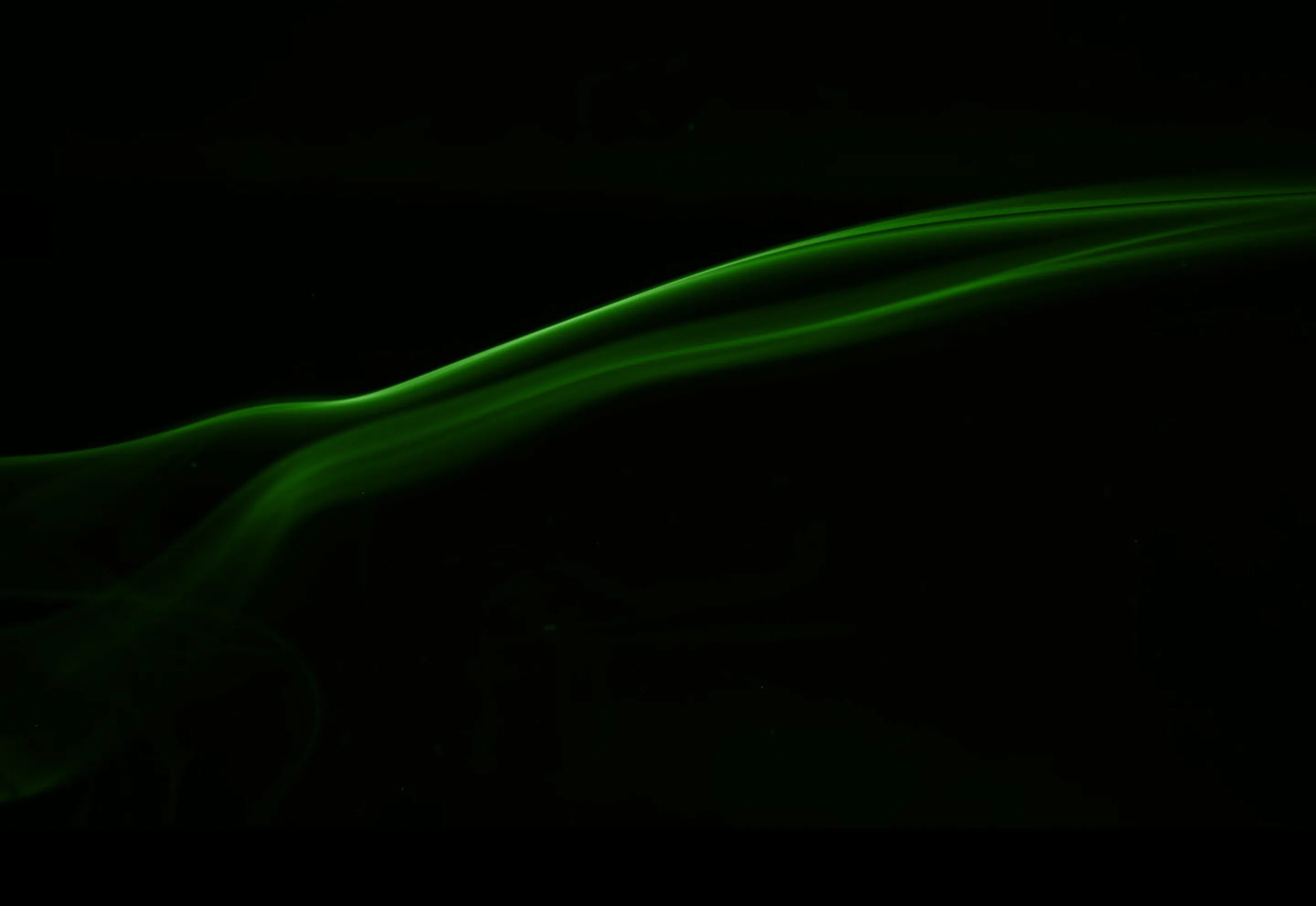 Thin, flowing green smoke trails on a black background.