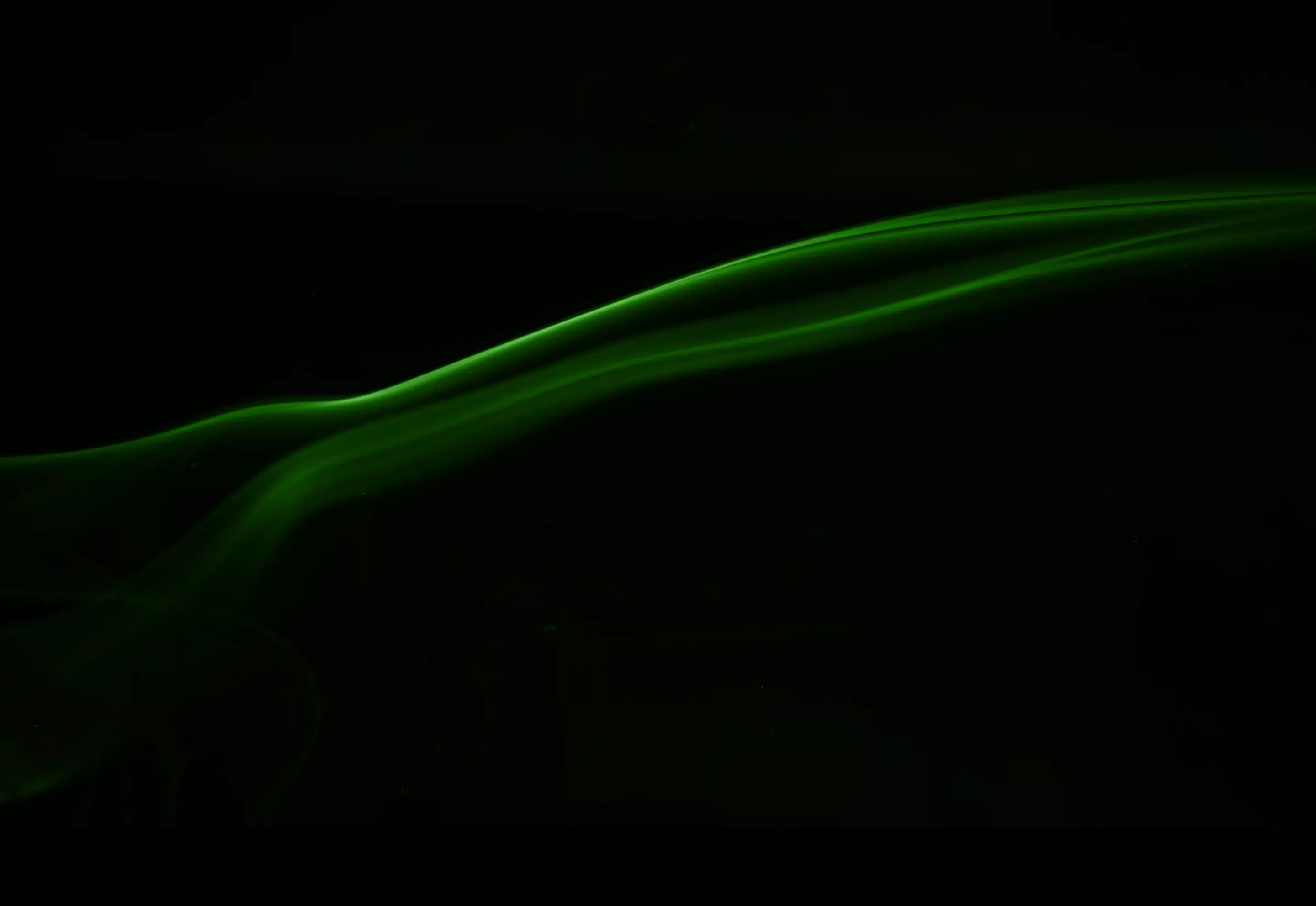 Thin, flowing green smoke trails on a black background.